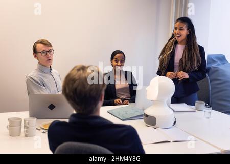 Geschäftsleute diskutieren während des Meetings über den Roboter-Sprachassistenten Stockfoto