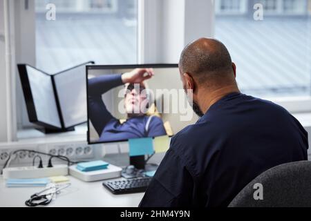 Männlicher Arzt mit Online-Konsultation mit älteren Patienten Stockfoto