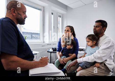 Männlicher Arzt im Gespräch mit der Familie mit Kindern Stockfoto