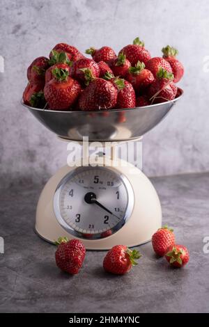 In einer Schupfschale werden frische, saftige Erdbeeren gewogen Stockfoto