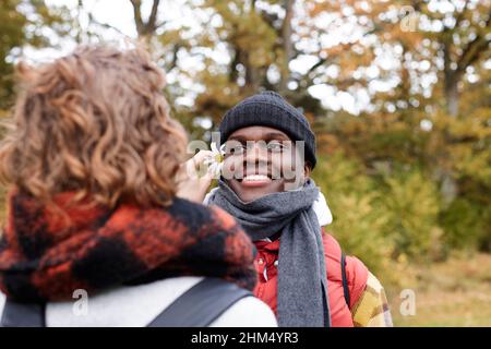 Frau, die Blume hinter das Ohr des Freundes stellt Stockfoto