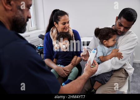 Männlicher Arzt untersucht Familie mit Kindern Stockfoto