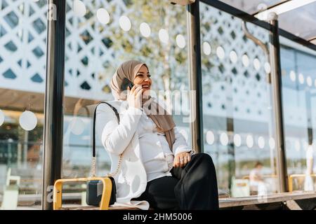 Frau, die an der Bushaltestelle über das Handy sprach Stockfoto