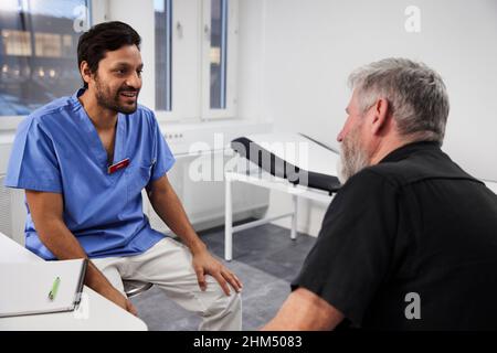 Männlicher Arzt, der während des Termins mit einem älteren Patienten spricht Stockfoto
