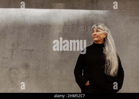Ältere Frau stand vor Gebäude Stockfoto