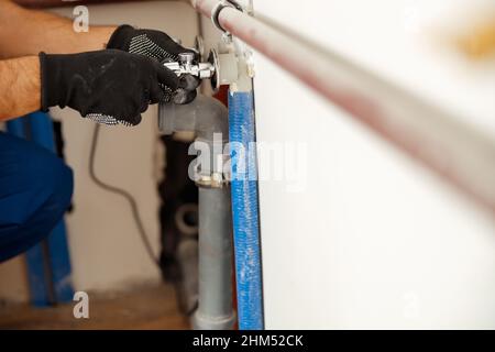 Nahaufnahme der Hände des Klempners, der Rohre überprüft, während das Heizsystem in der Wohnung installiert wird Stockfoto