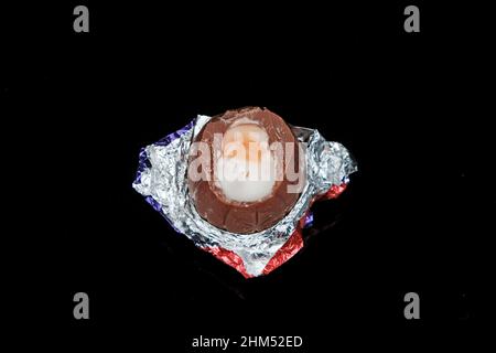 Cadbury Creme Ei (halb gegessen) auf schwarzem Hintergrund Stockfoto