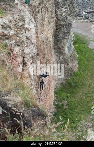 Ein Mitglied der Feuerwehr nähert sich im Rahmen einer Übung zur Bergung von Klippen einem Dummy an der Wand Stockfoto