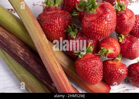 Erdbeeren und Rhabarber frisch geerntet, liegen auf einem alten Holztisch Stockfoto