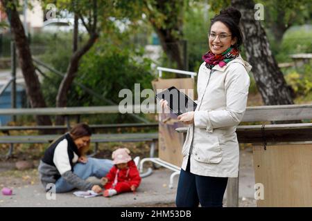 Frau am Spielplatz mit digitalem Tablet Stockfoto