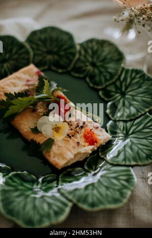 Cracker mit Kräutern und essbarer Blume auf Teller Stockfoto