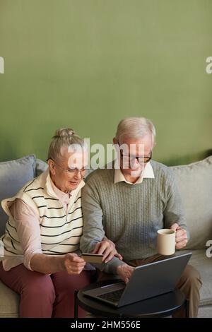 Lässige ältere Männer und Frauen sitzen auf der Couch vor dem Laptop und wählen Waren im Online-Shop zu Hause Stockfoto