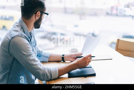 Nachdenklicher Unternehmer beim Lesen von Dokumenten im Café Stockfoto