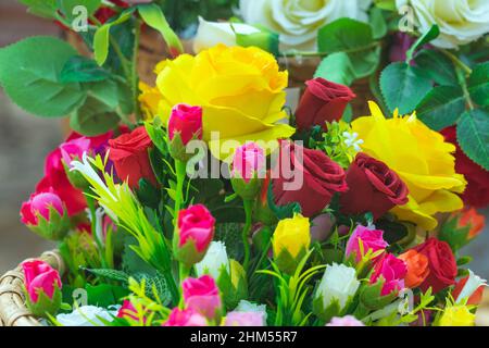 Schöne Bouquet Rosen Blume künstlich in vintage Weidenkorb. Künstliche mehrfarbige Blumen aus Stoff oder Stoff sehen aus wie echte Blumen. Ret Stockfoto