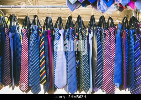 Große Auswahl an bunten Krawatten hängen in den Verkauf auf dem Straßenmarkt. Viele verschiedene Muster bunte Krawatten hängen auf Kleiderständer. Farbe Stockfoto