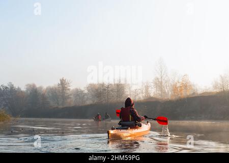 Menschen in Booten paddeln auf dem ruhigen Fluss, schöner sonniger Morgen Stockfoto