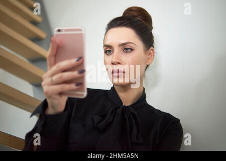 Junge professionelle Frau, die ihr Mobiltelefon im Büro benutzt Stockfoto