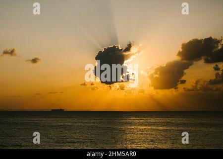 Sonnenuntergang am Goldenen Ozean mit Sonnenstrahlen hinter dem Wolkenboot Stockfoto