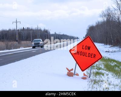 Orange Low Shoulder Schild entlang der Landstraße im Winter Stockfoto