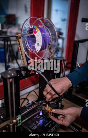 Hands of man lädt den 3D Printer mit einer Kunststoffspule Stockfoto