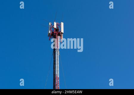 Telekommunikation roter Turm mit Antennen und blauem Himmel im Hintergrund. Kommunikationsgeräte für Mobiltelefone. Platz für Text oder Design kopieren Stockfoto