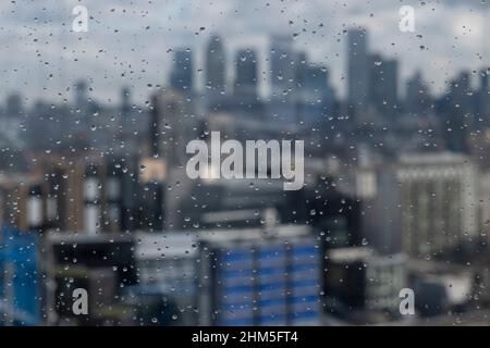 Blick durch Regentropfen auf Glas vom Garden at 120 in der City of London in Richtung Canary Wharf Geschäfts- und Finanzviertel am 4th. Februar 2022 in London, Großbritannien. Die City of London ist eine Stadt, ein zeremonieller Bezirk und ein kommunales Regierungsviertel, das das Hauptgeschäftsviertel CBD von London enthält. Die City of London wird allgemein einfach als die City bezeichnet, die umgangssprachlich auch als Square Mile bekannt ist. Im Laufe des letzten Jahrzehnts ist die Architektur der Stadt nach oben gewachsen, mit Wolkenkratzern, die die jetzt überfüllte Skyline füllen, und mit g nach oben skaliert Stockfoto