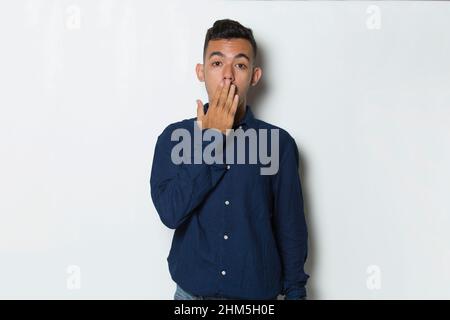 Junger Geschäftsmann schockierte den Mund aus Versehen mit Händen zu bedecken. Geheimes Konzept. Stockfoto