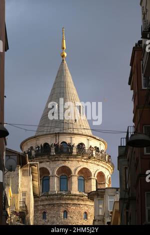Istanbul, Türkei - 29. Dezember 2022 : Touristen mit medizinischen Masken am Galata-Turm. Sie beobachten die Landschaft Istanbuls bei Sonnenuntergang. Stockfoto