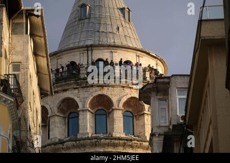 Istanbul, Türkei - 29. Dezember 2022 : Touristen mit medizinischen Masken am Galata-Turm. Sie beobachten die Landschaft Istanbuls bei Sonnenuntergang. Stockfoto