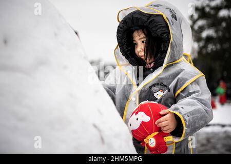 Wuhan, China. 07th. Februar 2022. Ein Mädchen spielt mit dem Winter-Paralympischen Maskottchen Shuey Rhon Rhon in Peking 2022 im Jiangtan Park während eines Schneefalls in Hubei.Wuhan leitete den ersten Schneefall des chinesischen Neujahrs ein. Kredit: SOPA Images Limited/Alamy Live Nachrichten Stockfoto