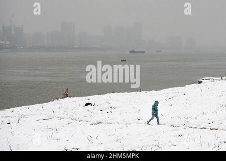 Wuhan, China. 07th. Februar 2022. Ein Mann geht während eines Schneefalls in Hubei im Jiangtan Park spazieren.Wuhan leitete den ersten Schneefall des chinesischen Neujahrs ein. Kredit: SOPA Images Limited/Alamy Live Nachrichten Stockfoto