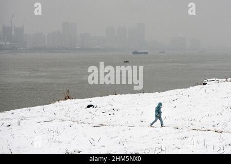 Wuhan, China. 07th. Februar 2022. Ein Mann geht während eines Schneefalls in Hubei im Jiangtan Park spazieren.Wuhan leitete den ersten Schneefall des chinesischen Neujahrs ein. (Foto von Ren Yong/SOPA Images/Sipa USA) Quelle: SIPA USA/Alamy Live News Stockfoto