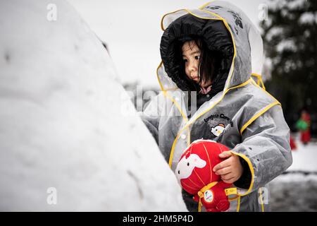 Wuhan, China. 07th. Februar 2022. Ein Mädchen spielt mit dem Winter-Paralympischen Maskottchen Shuey Rhon Rhon in Peking 2022 im Jiangtan Park während eines Schneefalls in Hubei.Wuhan leitete den ersten Schneefall des chinesischen Neujahrs ein. (Foto von Ren Yong/SOPA Images/Sipa USA) Quelle: SIPA USA/Alamy Live News Stockfoto