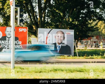 Kehl, Deutschland - 24. Sep 2021: Ein Auto fährt mit den Kanzlerkandidaten der SPD mit Olaf Scholz und CDU Wolfgang Schaeuble an großen Wahlplakaten vorbei. Am 26.09.2021 werden die deutschen Bürger aufgerufen, einen neuen Bundestag zu wählen. Stockfoto