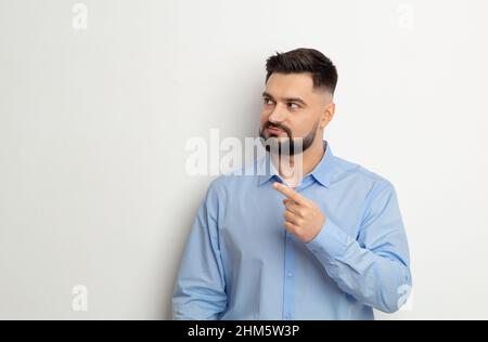 Porträt eines Mannes, der mit dem Finger zeigt und den Kopierraum auf weißem Hintergrund zeigt. Stockfoto