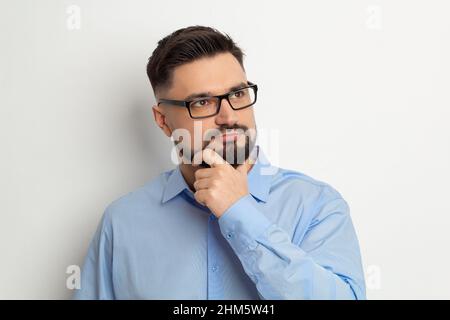 Porträt eines denkenden Geschäftsmanns mit einem Bart auf weißem Hintergrund. Nachdenklich über die Idee eines Mannes. Stockfoto