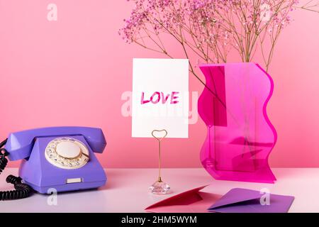 Valentinstag-Konzept. Karte mit Wort Liebe. Retro-Telefon, Vase mit getrockneten Blumen, Umschläge mit Grußkarten, Geschenkgutscheine. Romantische Überraschung vom Liebhaber. Hochwertige Fotos Stockfoto