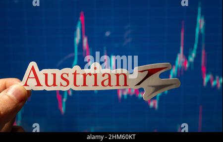 10. November 2021, Wien, Österreich. Emblem der Austrian Airlines vor dem Hintergrund einer Aktienkurskarte. Stockfoto