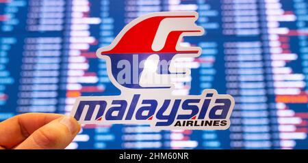 11. Dezember 2021, Subang, Malaysia. Das Emblem der Malaysia Airlines vor dem Hintergrund einer elektronischen Anzeigetafel mit Flugplänen auf der i Stockfoto