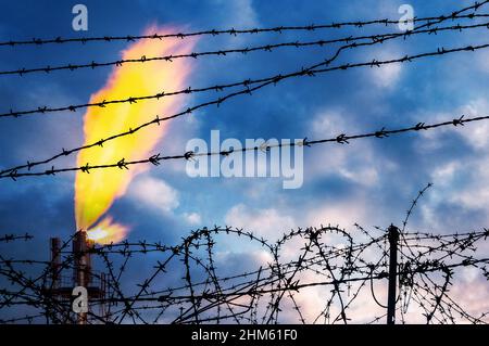 Schornstein der Industriegasanlage hinter Stacheldrahtzaun. Energiekrise, Russland, Ukraine-Konflikt, Nord Stream 2, Europa, Russisches Gas... Konzept Stockfoto