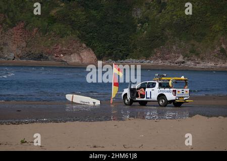 Rettungsschwimmer sitzt in einem RNLI 4 x 4 Fahrzeug an einem Strand in Großbritannien und beobachtet Schwimmer, mit Warnflaggen Stockfoto