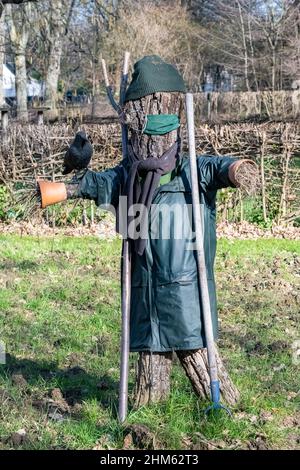 Eine Vogelscheuche auf einem Feld, mit einer Krähe Stockfoto