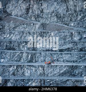 Stufenwand aus Diabasestein-Steinbruch mit roter Bohrinsel auf einer Bank Stockfoto