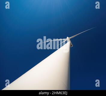 Dreiblätterige Windturbine vor tiefblauem Himmel, Blick nach oben mit dramatischer Perspektive Stockfoto