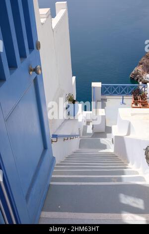 Santorini, Griechenland - 7. Mai 2021 : Eine Tür und eine Treppe führen zu einem Wohngebäude mit einem schönen Blick auf die Ägäis und den Vulkan Santor Stockfoto