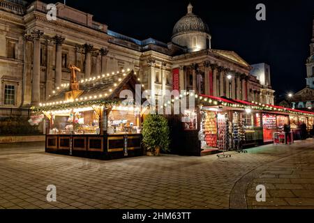 Die farbenfrohen Weihnachtsmarktstände vor der National Gallery am Trafalgar Square in London sehen nachts toll aus Stockfoto