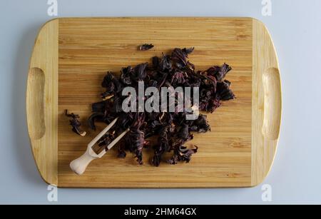 Tee aus getrockneten Granatapfelblüten. Erhöht die Immunität. Holzspatel mit Tee und einer Handvoll Teemischung auf einem Holzbrett. Stockfoto