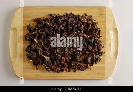 Tee aus getrockneten Granatapfelblüten. Erhöht die Immunität. Hintergrund von duftendem Tee auf einem Holzbrett. Stockfoto