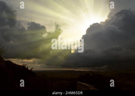 Wolkenbild von dunklen, stürmischen Wolken am blauen Himmel mit Sonnenstrahl. Die Strahlen der Sonne nach dem Regen. Landschaft mit den Strahlen der Sonne, die durch Th Stockfoto