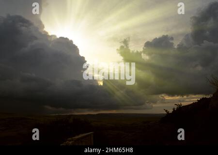 Wolkenbild von dunklen, stürmischen Wolken am blauen Himmel mit Sonnenstrahl. Die Strahlen der Sonne nach dem Regen. Landschaft mit den Strahlen der Sonne, die durch Th Stockfoto